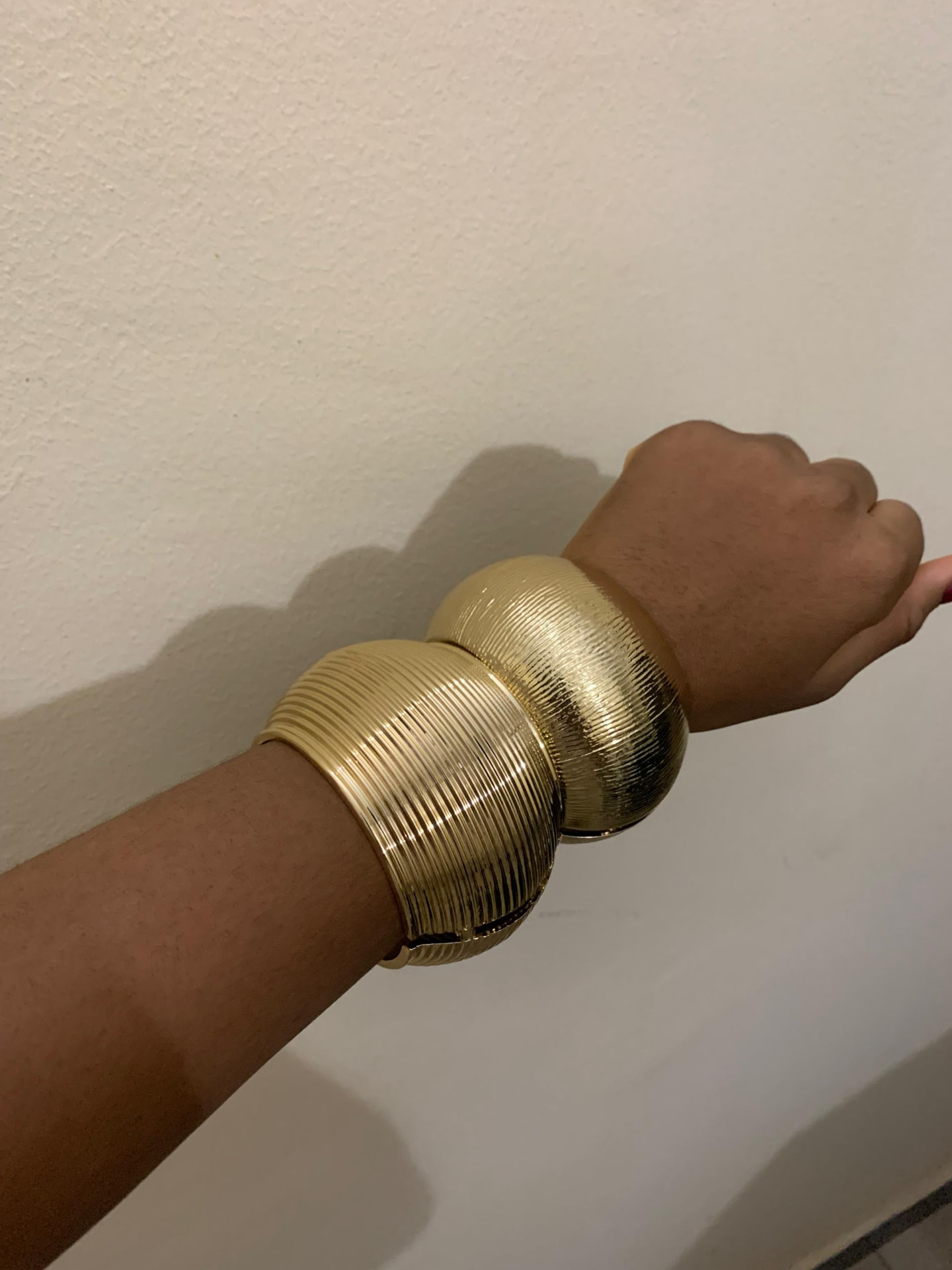 Two textured gold cuffs stacked on a wrist
