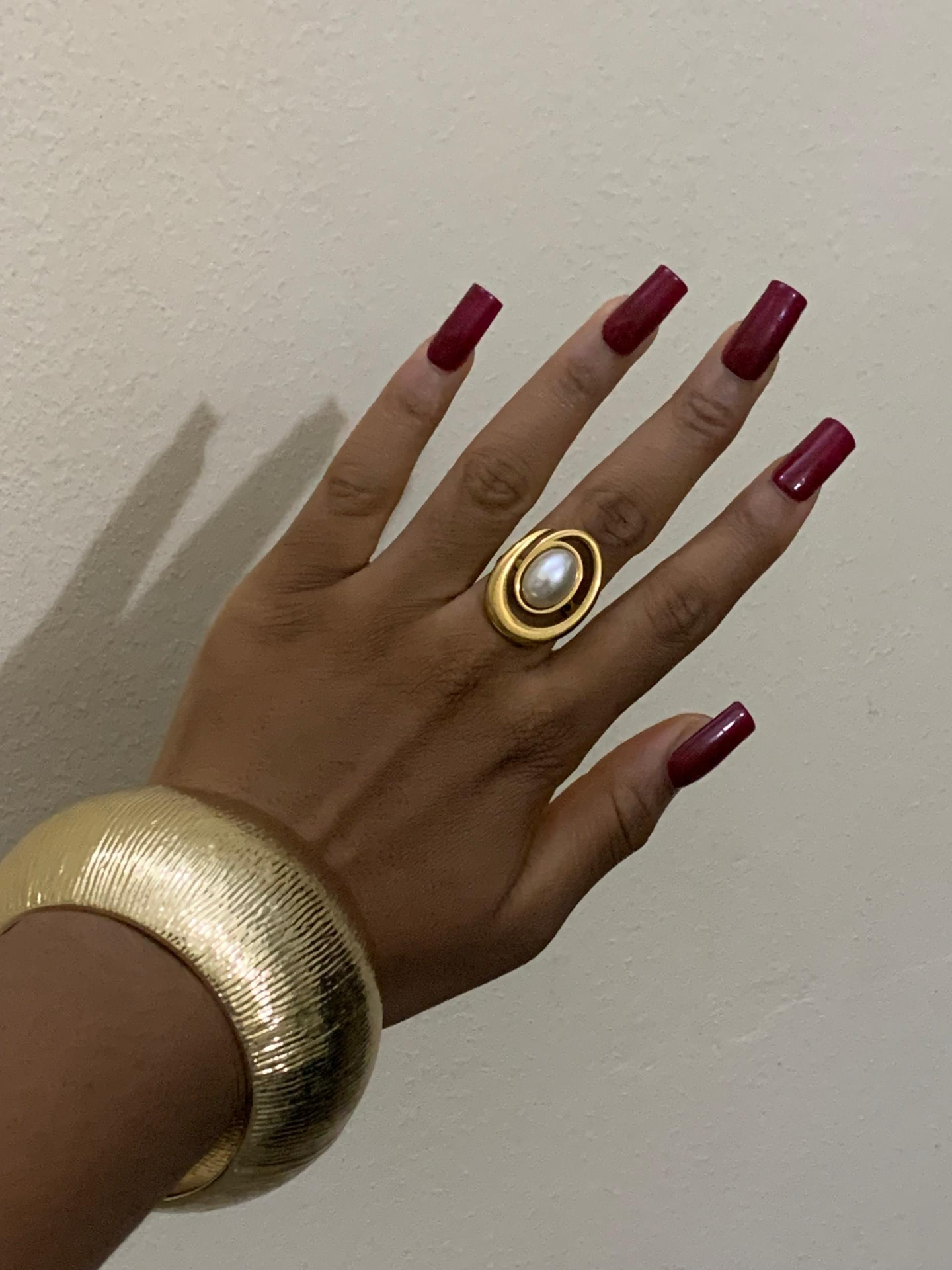 A pearl statement ring and wide gold cuff worn together
